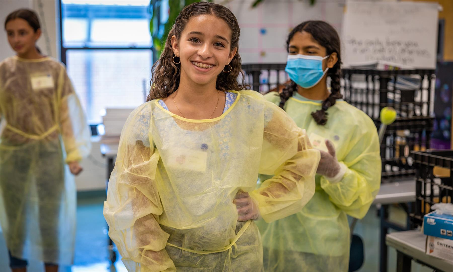 A girl smiles while wearing personal protective equipment